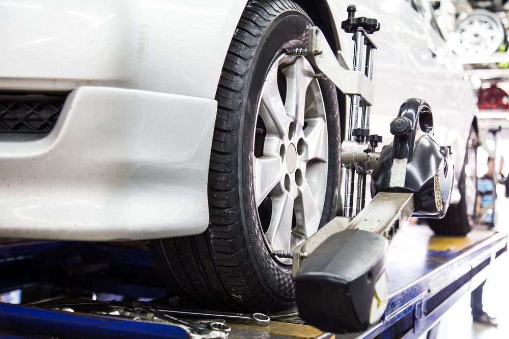 A Car Is Being Adjusted on A Lift in A Garage — Rasmussen Mechanical & Tyres in Garbutt, QLD