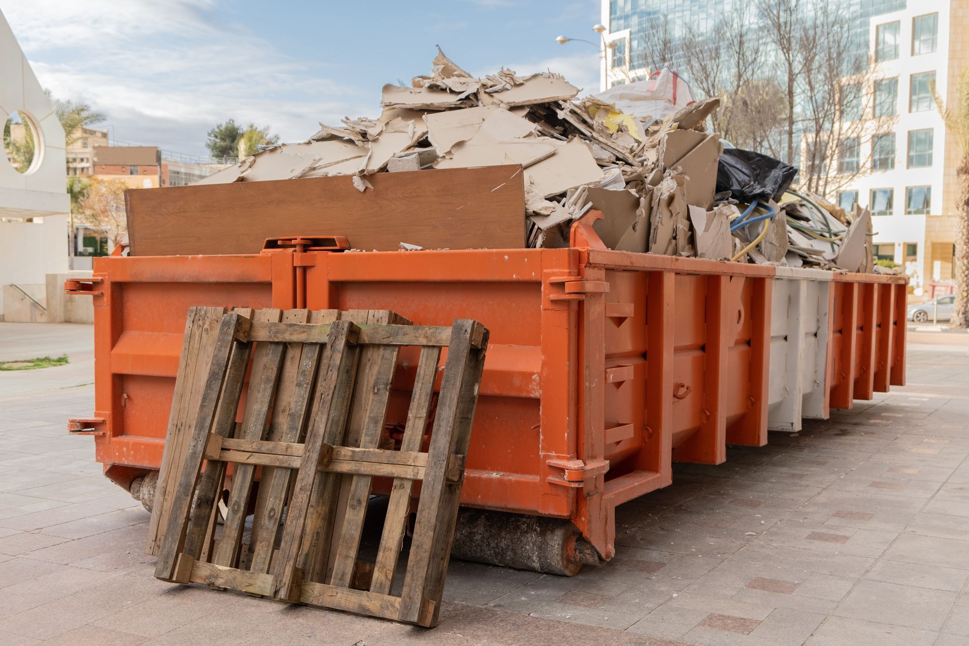 a large orange dumpster filled with cardboard and wooden pallets .