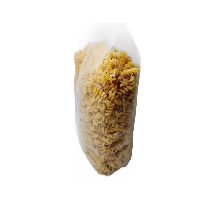 Bolsa de plástico transparente llena de pasta espiral cruda sobre un fondo blanco.