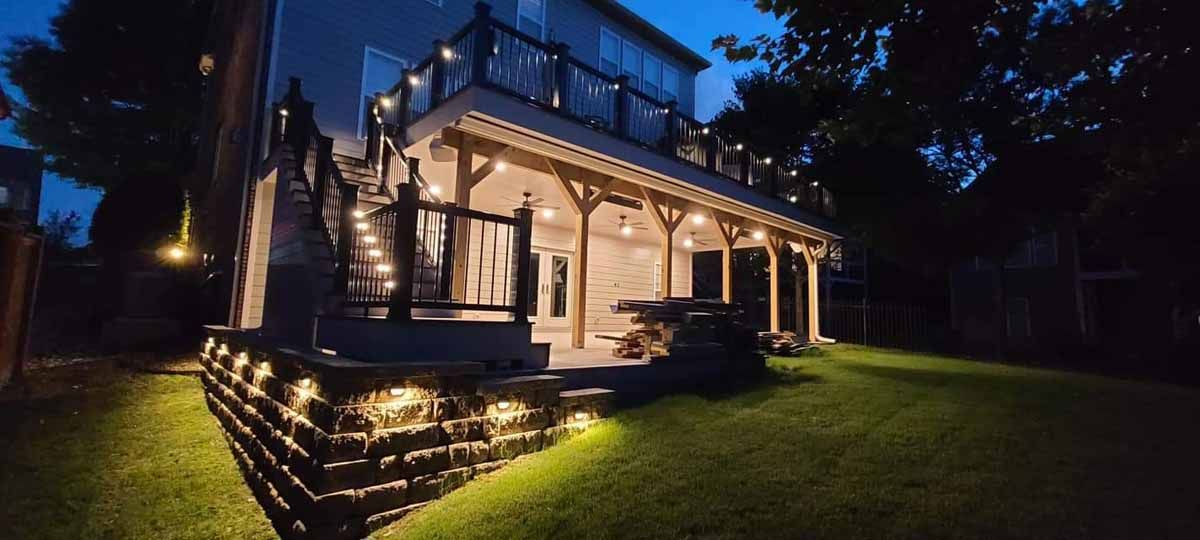 A large house with a large deck is lit up at night.