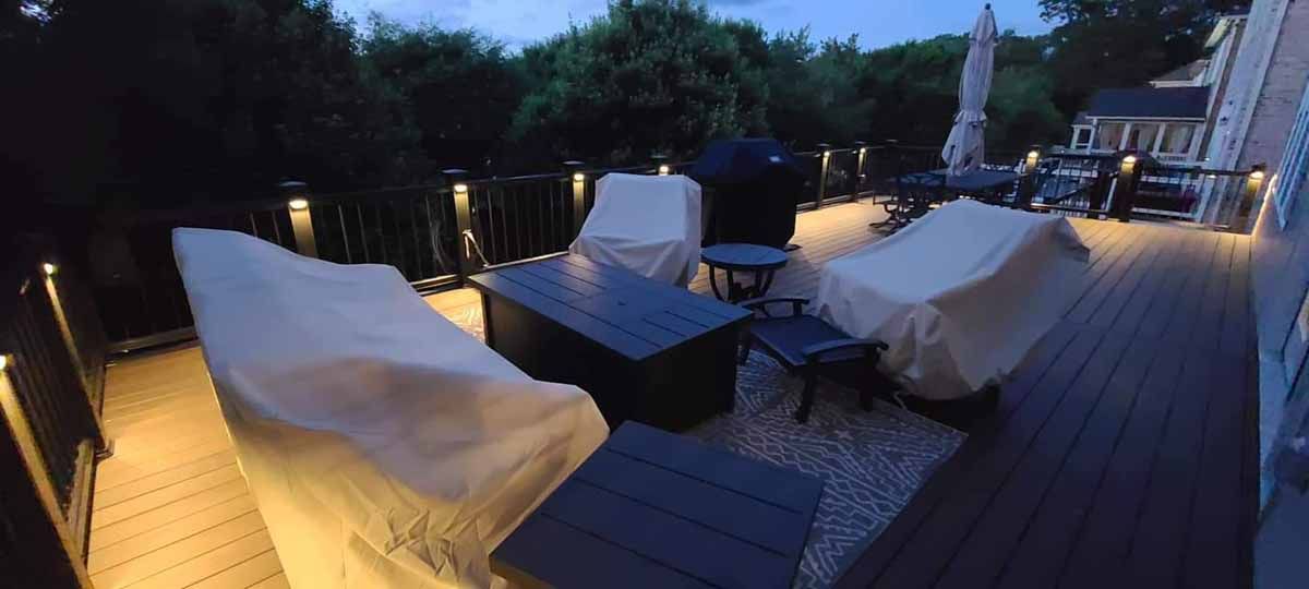 A wooden deck with a lot of furniture on it at night.
