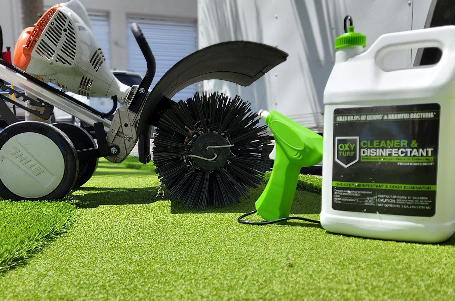 Chainsaw, brush cutter, and weed killer bottle on artificial grass outdoors