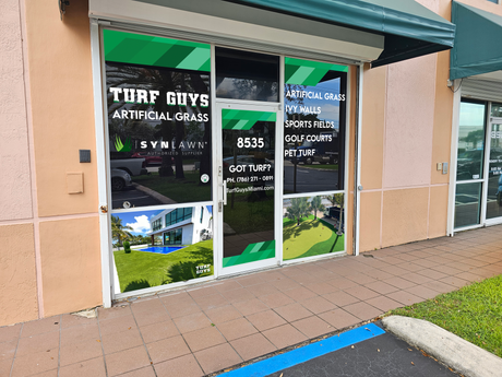 Storefront for Turf Guys Artificial Grass with glass doors and green signage on a sidewalk.