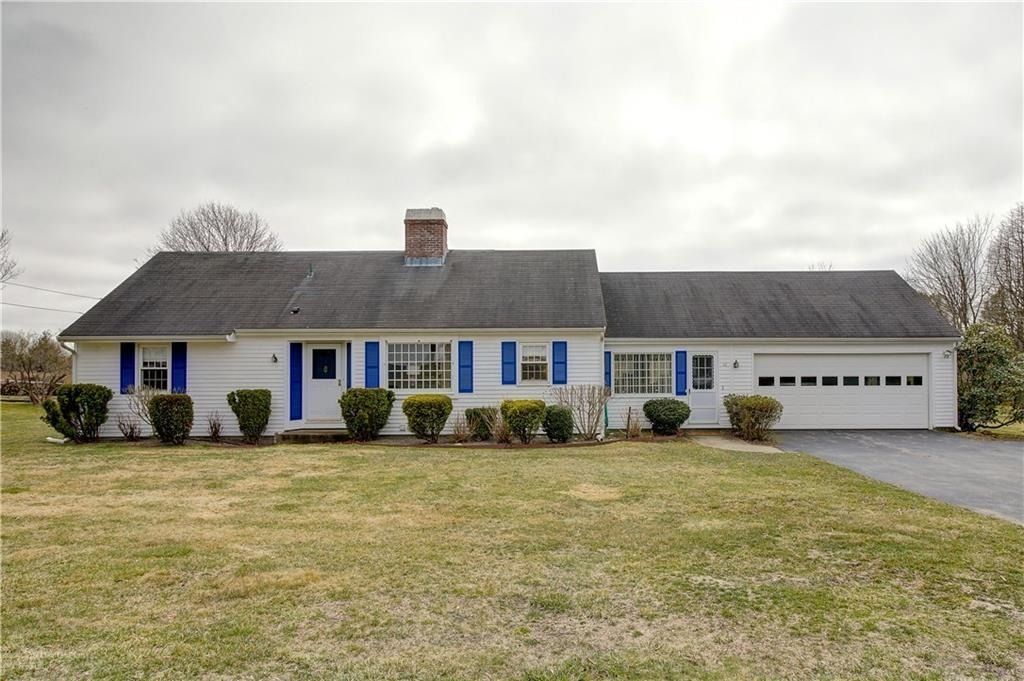 Single-story blue house with white trim, front lawn, and attached garage under a cloudy sky