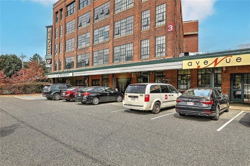 Brick hotel facade with parked cars and a café entrance along the street