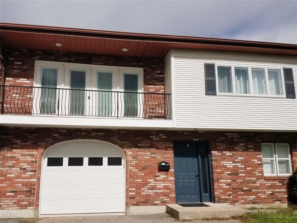 Two-story brick house with white siding, balcony, garage, and blue front door