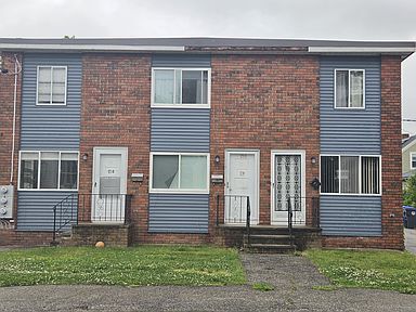 Row of brick-and-blue townhouse apartments with front doors and small lawns