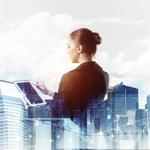 Woman using a tablet against a translucent city skyline and data graphics