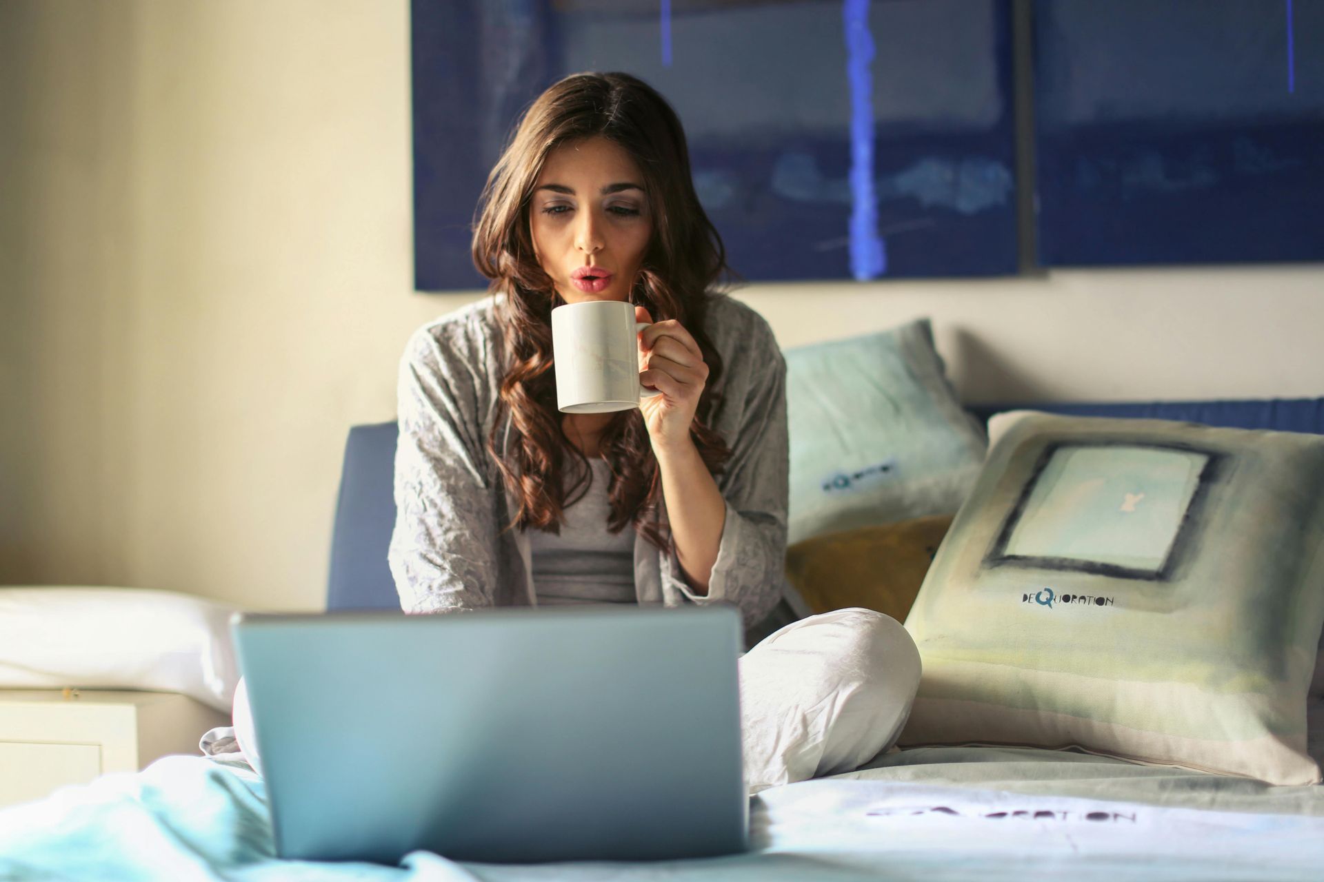 Small business owner who is a woman drinking out of a mug on her computer