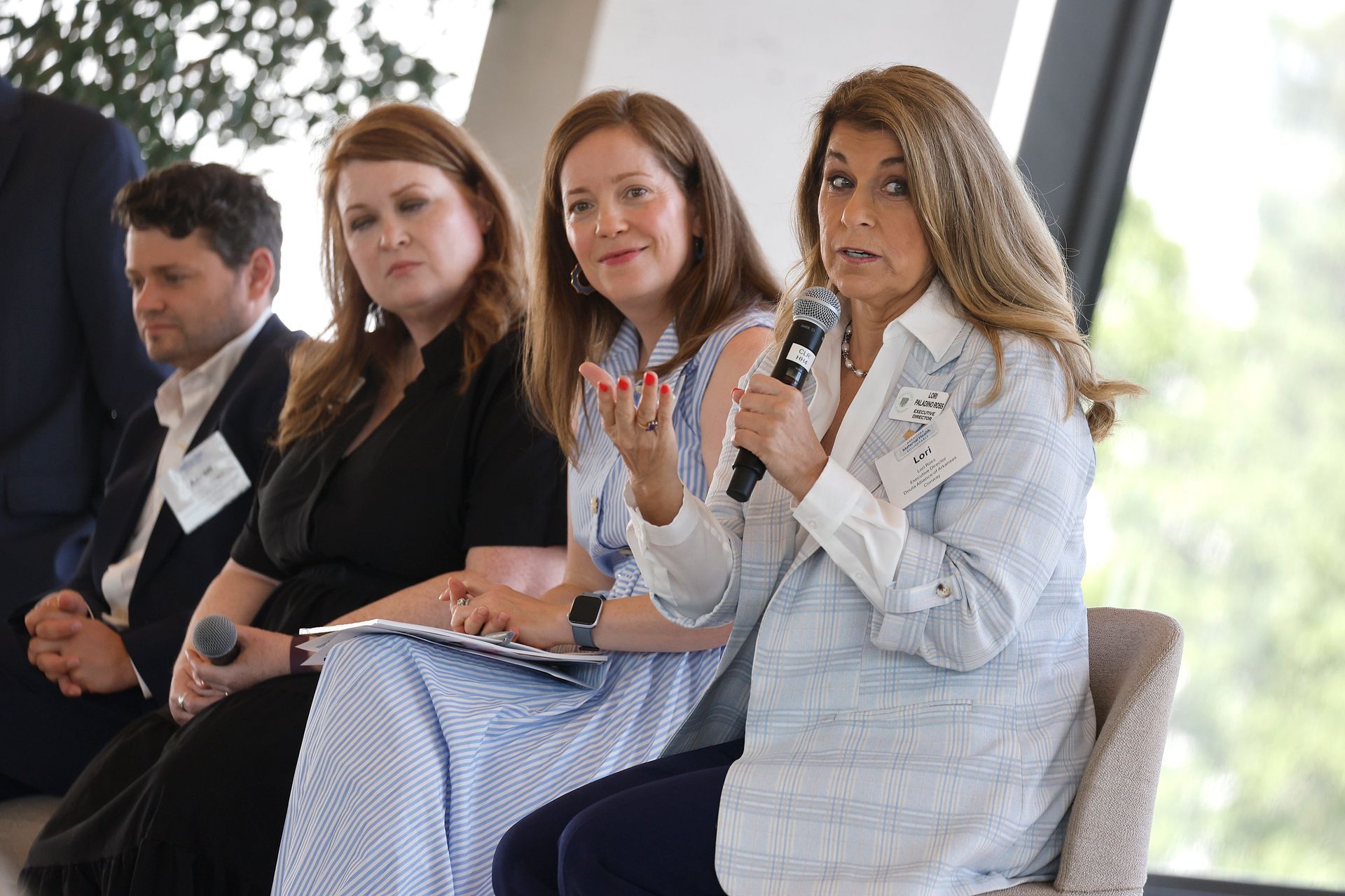 Panel discussion with four speakers seated on stage, one woman speaking into a microphone.