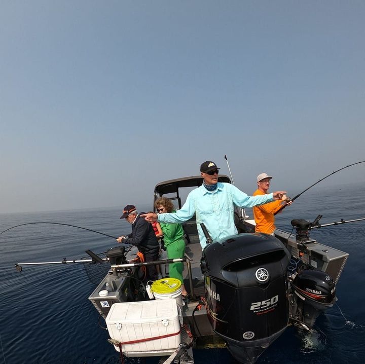 People fishing from a boat on a calm sea. The sky is hazy.