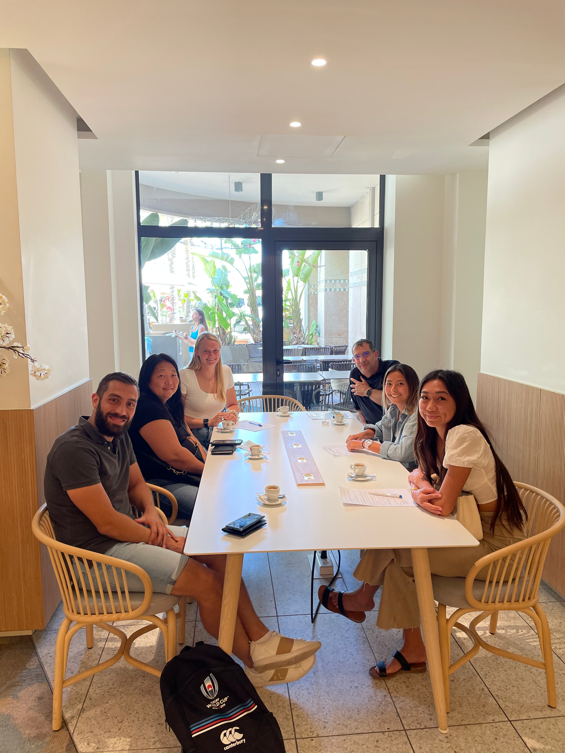 People seated at a table in a cafe, looking at the camera.