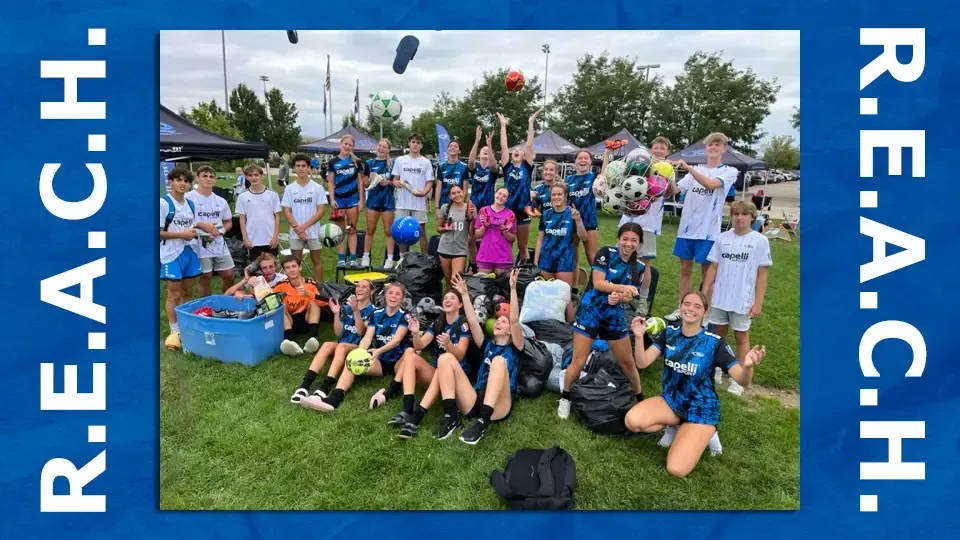 Soccer team celebrates with a group photo outdoors, some throwing items in the air.