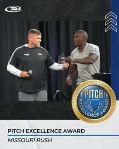 Two men shaking hands on stage;