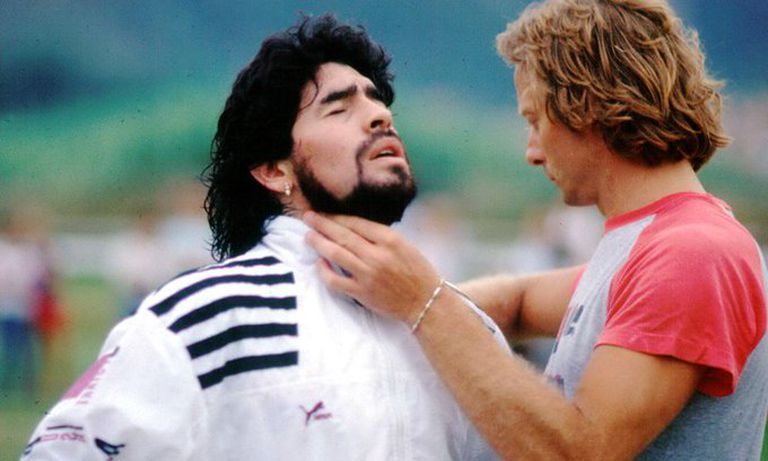 Diego Maradona having his collar adjusted by a man in an outdoor setting.