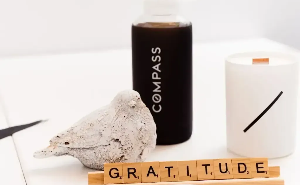 A compass bottle, a bird statue, and a candle on a table