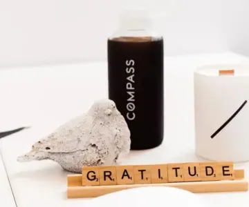 A compass bottle, a bird statue, and a candle on a table