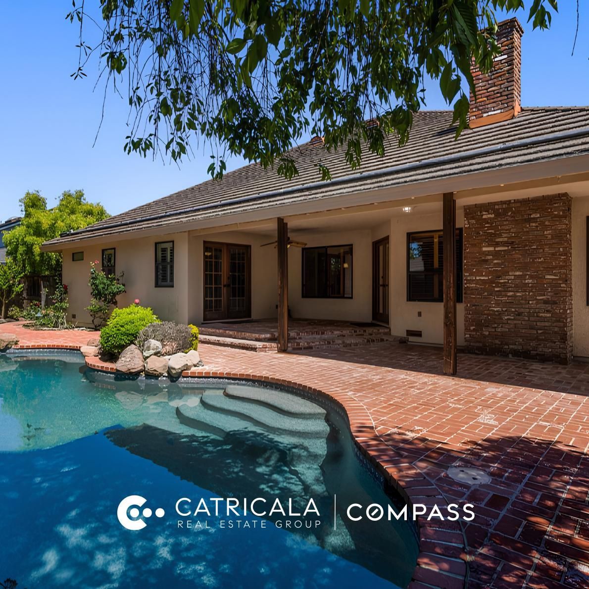 Backyard with a pool, brick patio, single-story home, and Catricala Real Estate Group and Compass logo overlay.