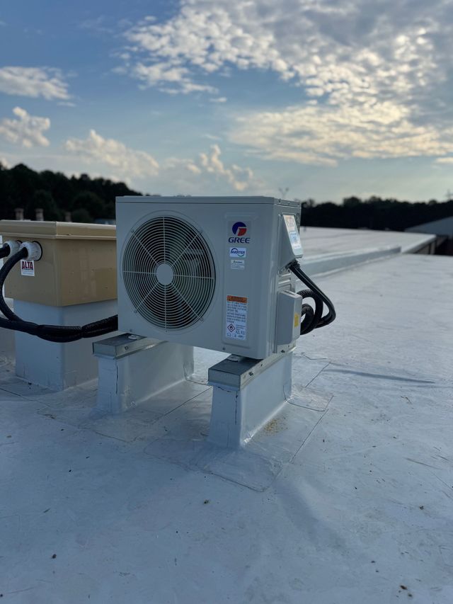 White rooftop HVAC unit with fan on a flat roof under a cloudy sky