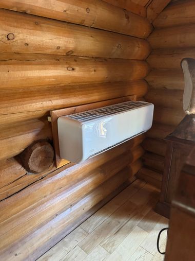 Log cabin interior with a wall-mounted white radiator and wooden floorboards