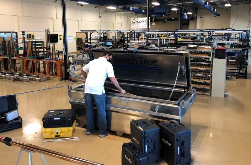 A man is working on a metal box in a factory.