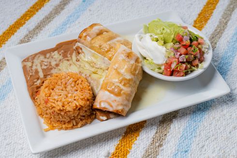 Plate with enchiladas, rice, refried beans, and a side salad on a striped cloth.