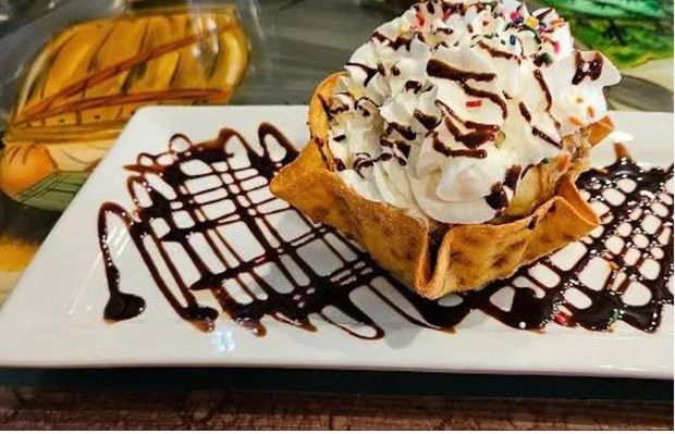Fried ice cream drizzled with chocolate syrup on a white plate