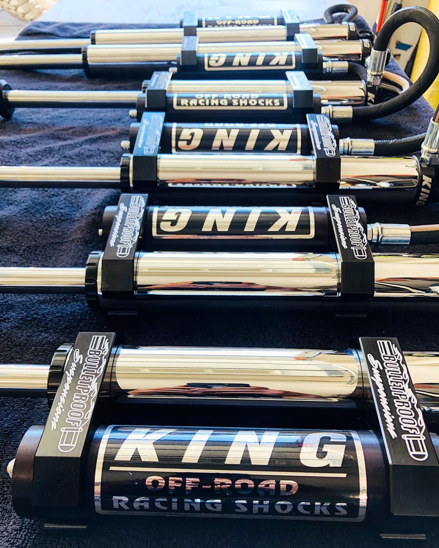 Four high-performance King off-road racing shock absorbers with reservoirs lined up on a dark surface.