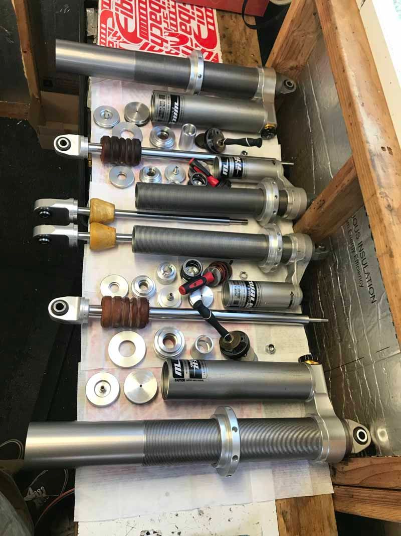 Disassembled high-performance suspension shocks and assorted hardware laid out on a workbench.