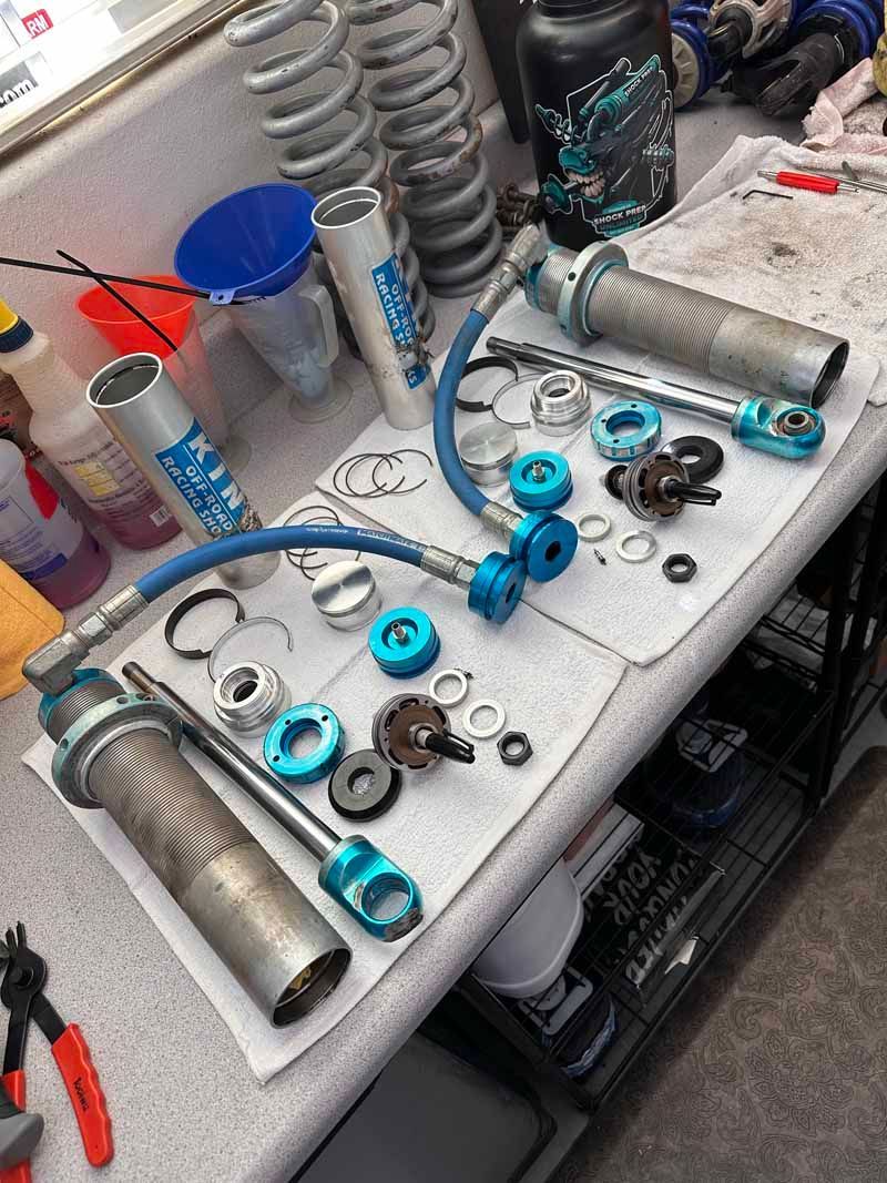 Disassembled automotive suspension components, including springs and shocks, laid out on a workshop workbench for service.