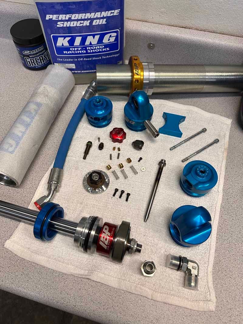 Disassembled King Performance shock absorber components and tools laid out on a white cloth on a workbench.