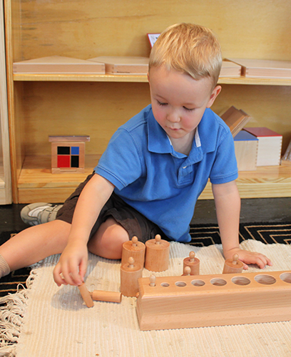 A young boy in a blue shirt is playing with wooden blocks