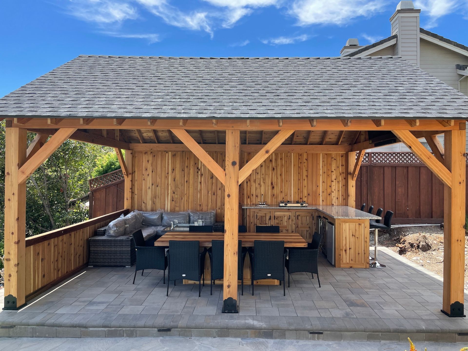A wooden pavilion with a table and chairs underneath it