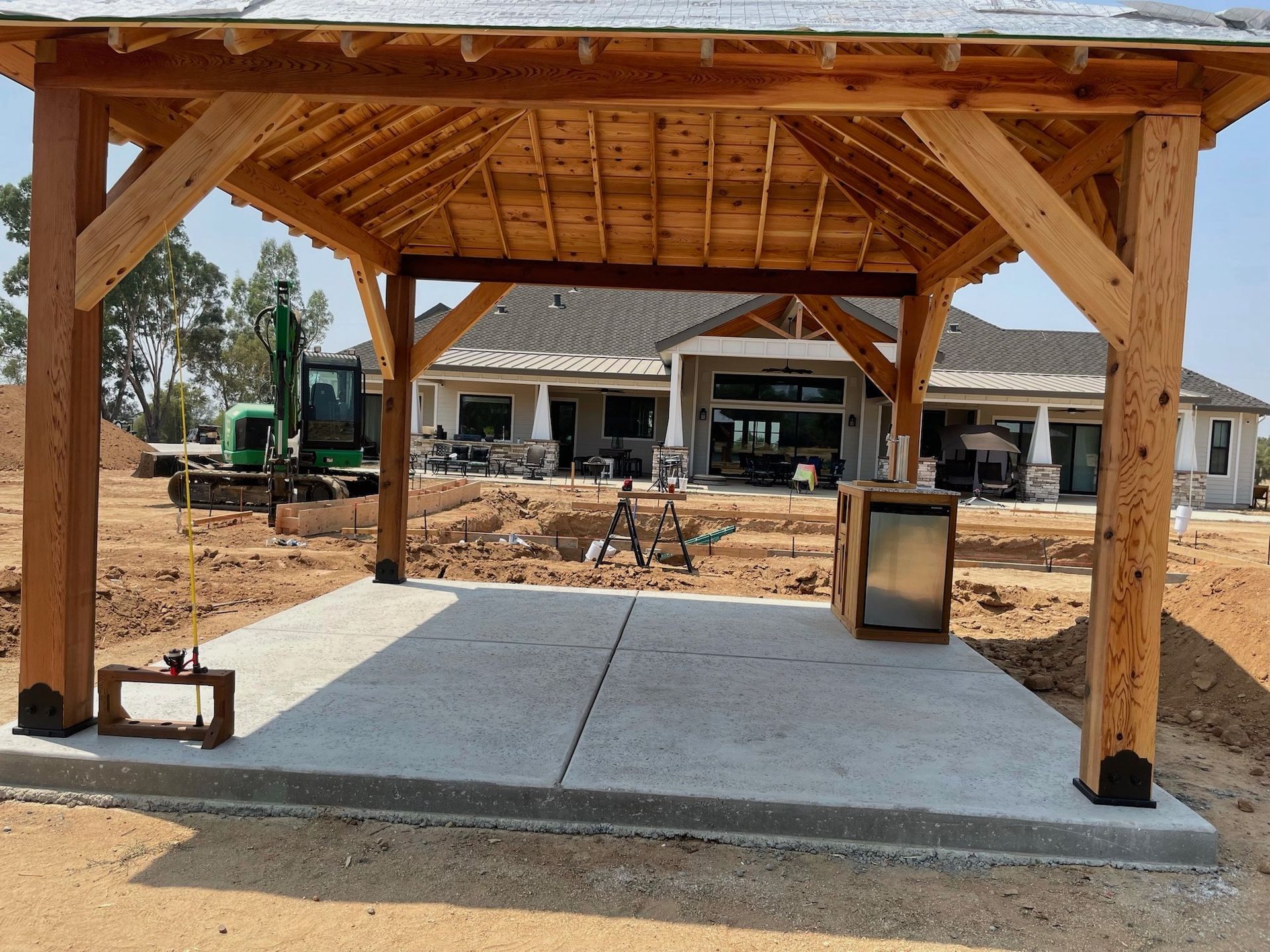 A wooden pavilion is being built in front of a house under construction