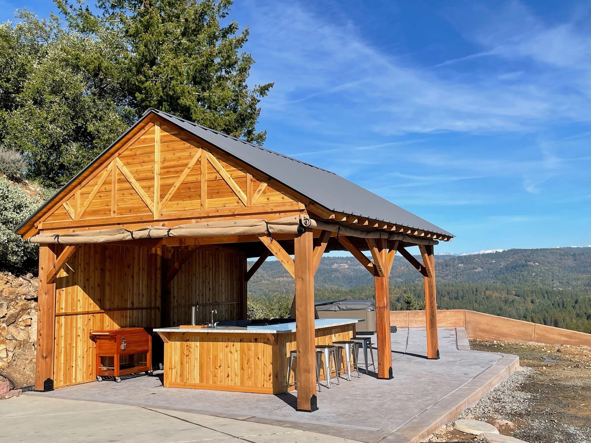 A wooden pavilion with a table and chairs underneath it