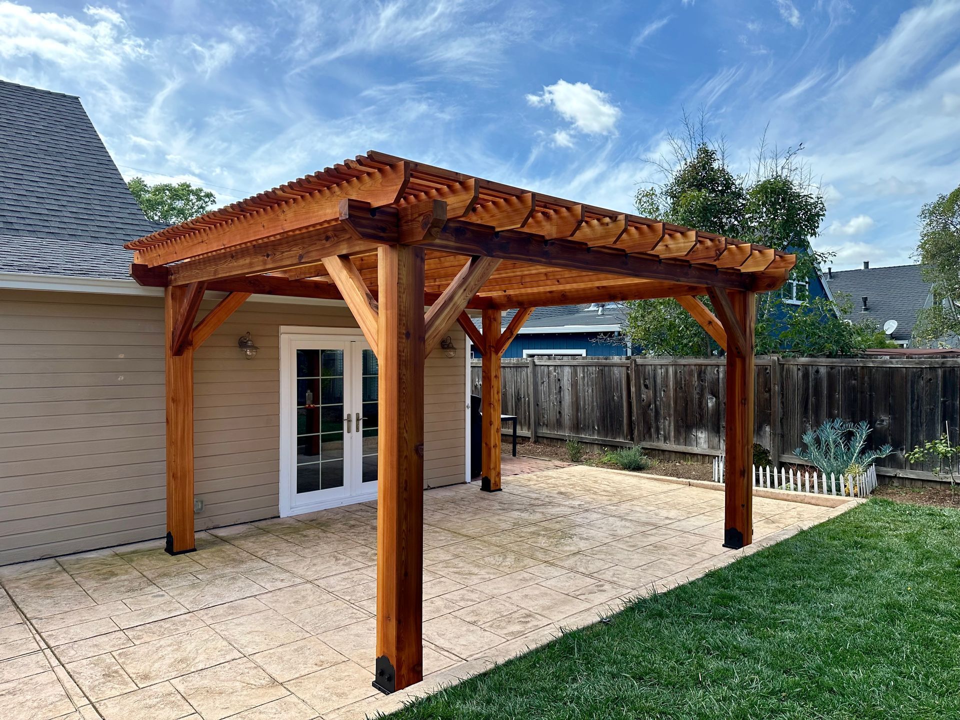 A wooden pergola is in the backyard of a house.