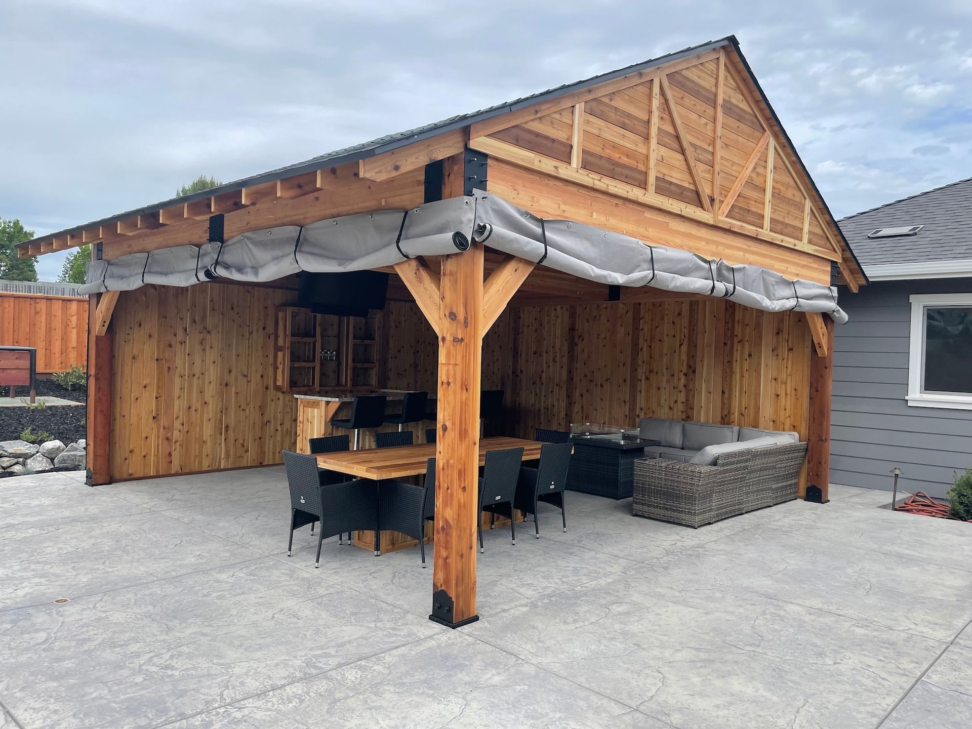 A wooden pavilion with a table and chairs underneath it.