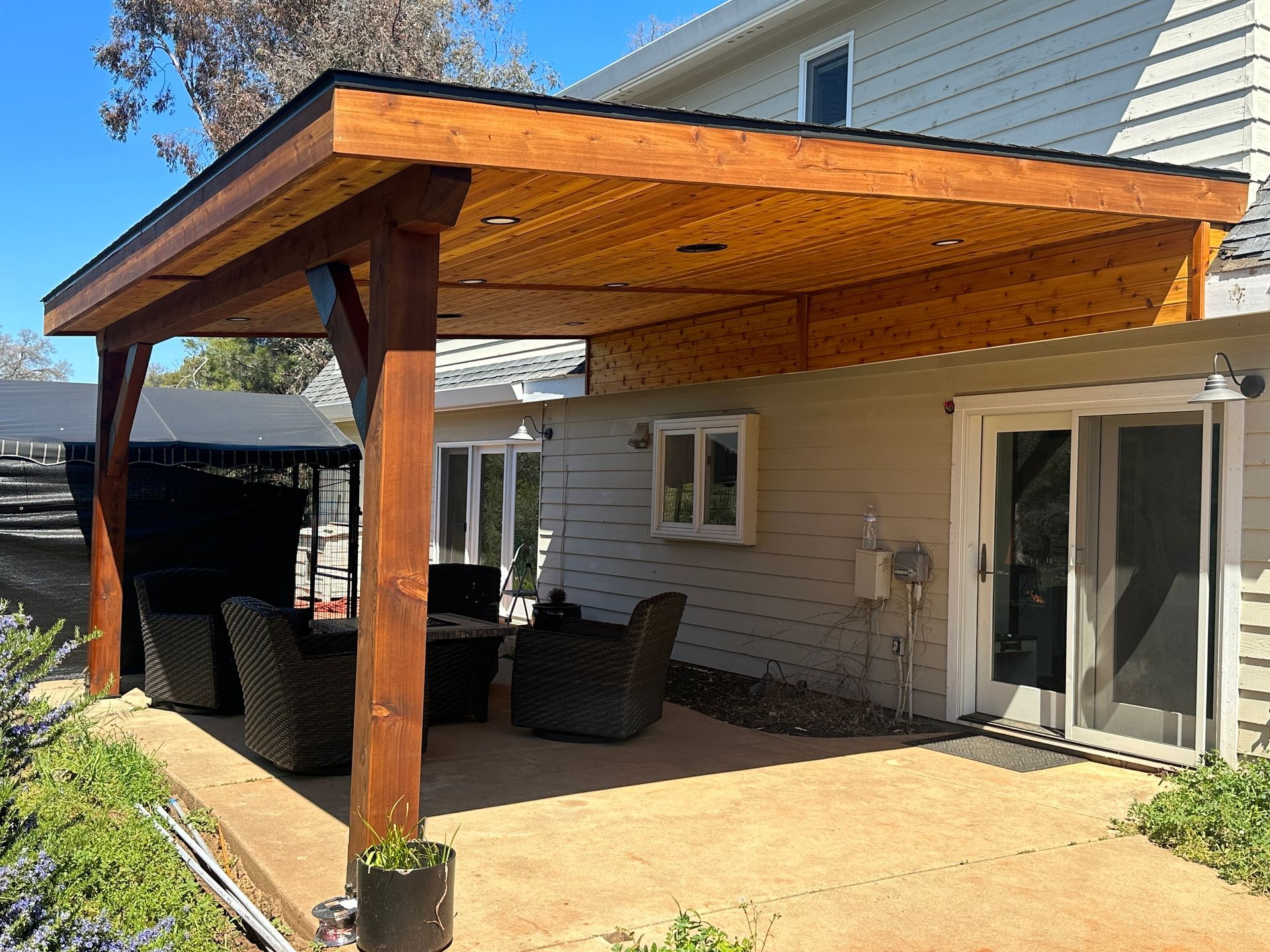 A wooden patio with chairs and a table in front of a house.