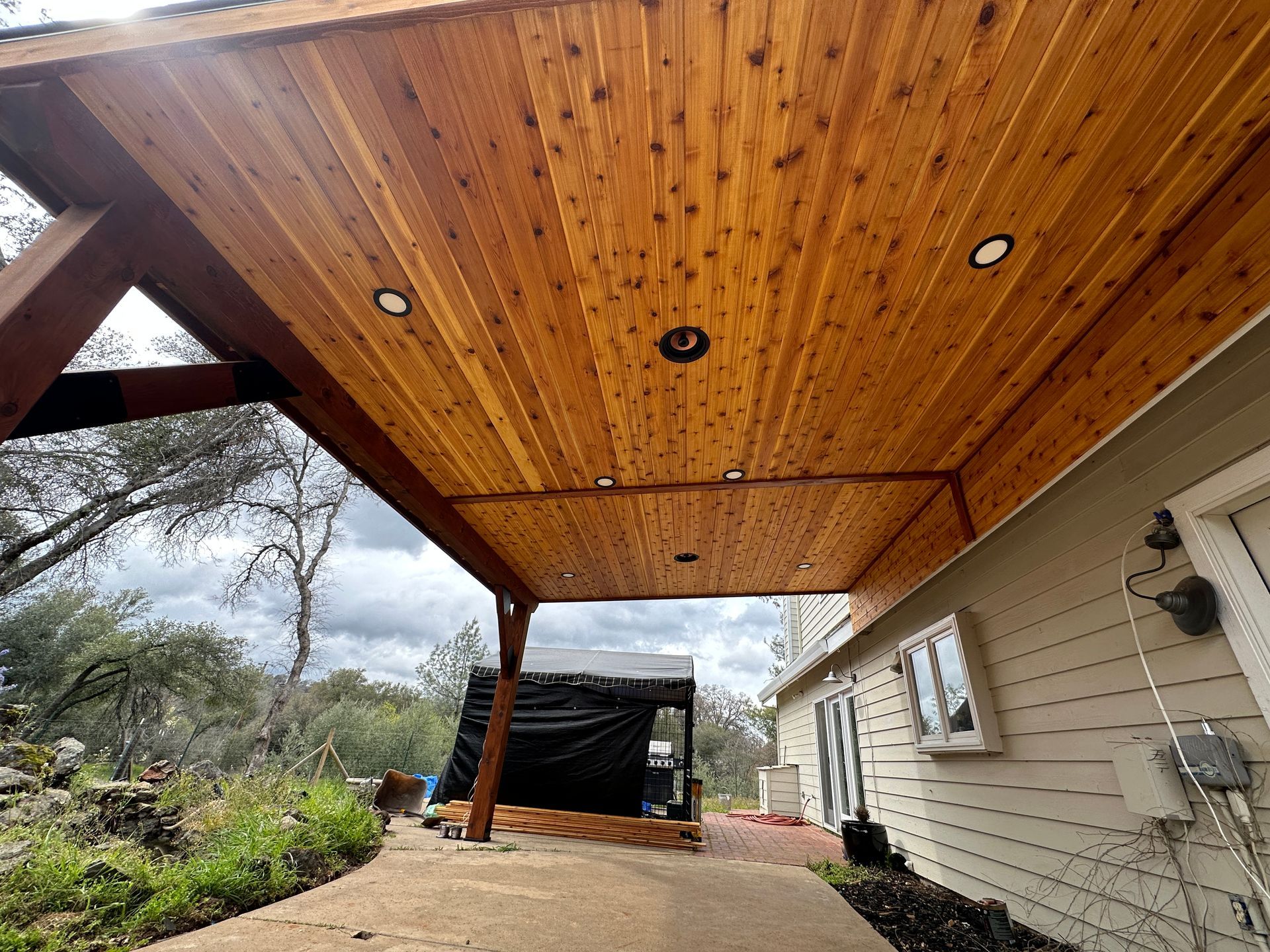 A wooden covered walkway leading to a house with a wooden ceiling.