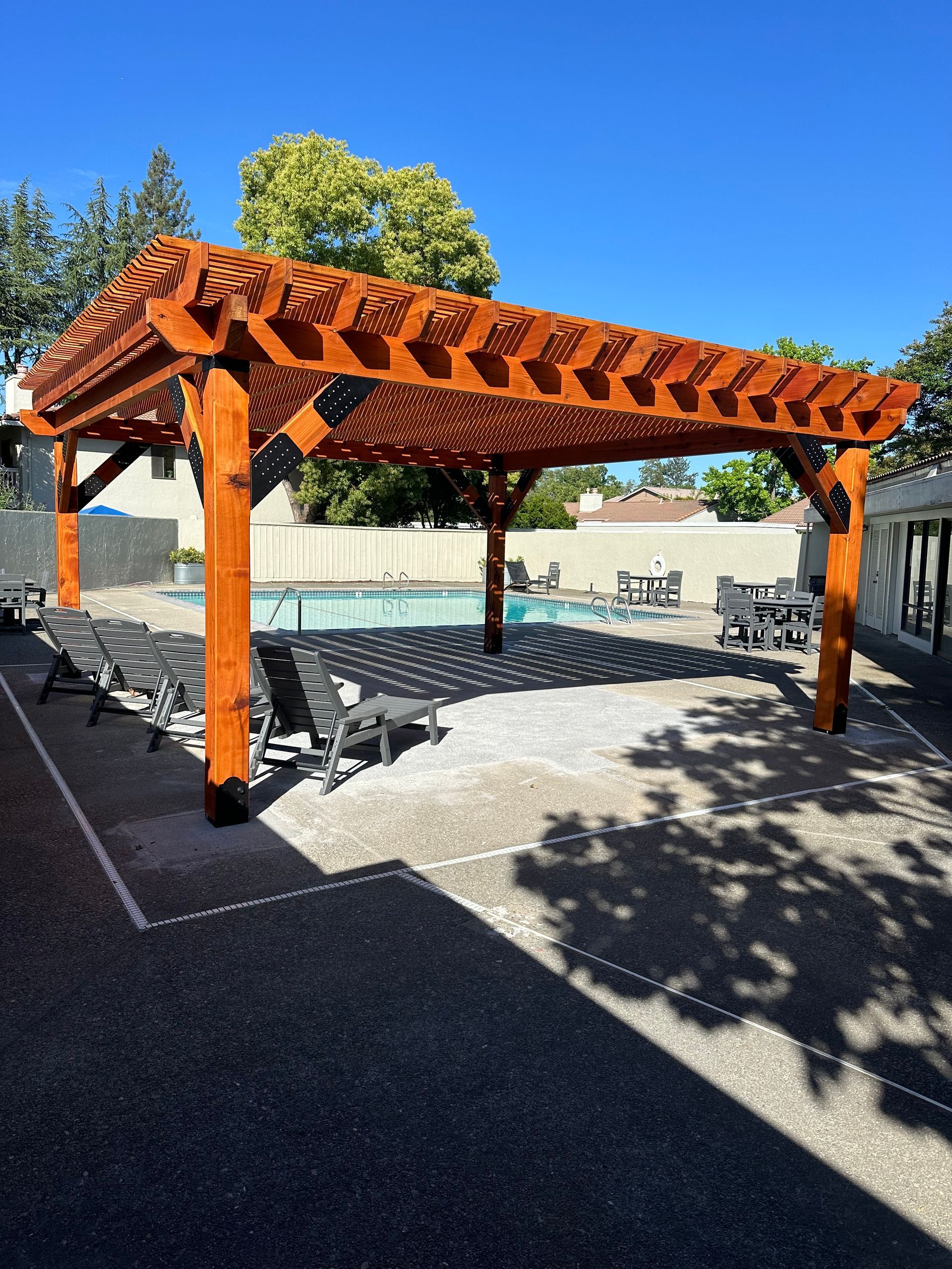 A large wooden pergola over a swimming pool