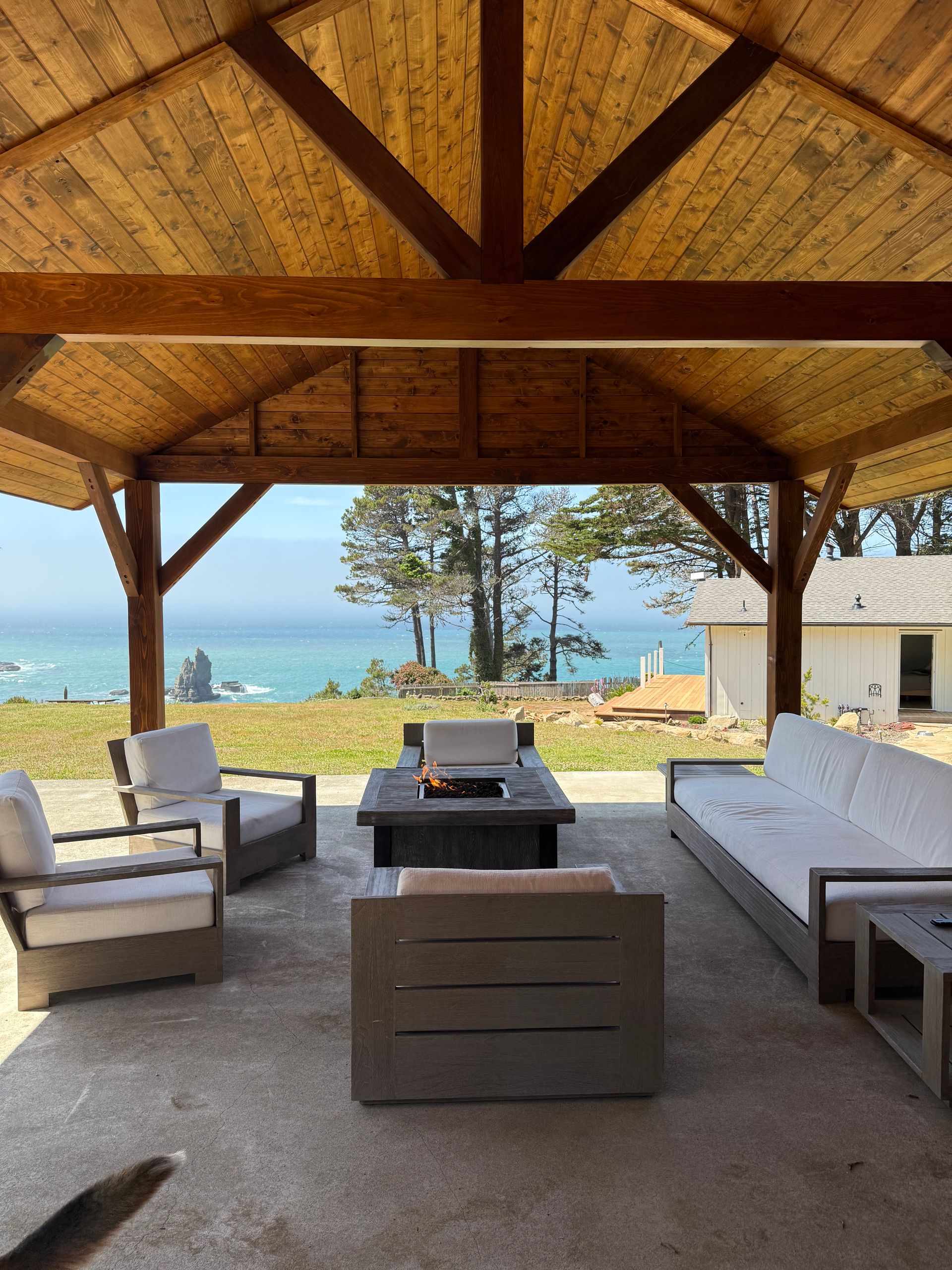 Outdoor seating area with a view of the ocean under a wooden pergola.