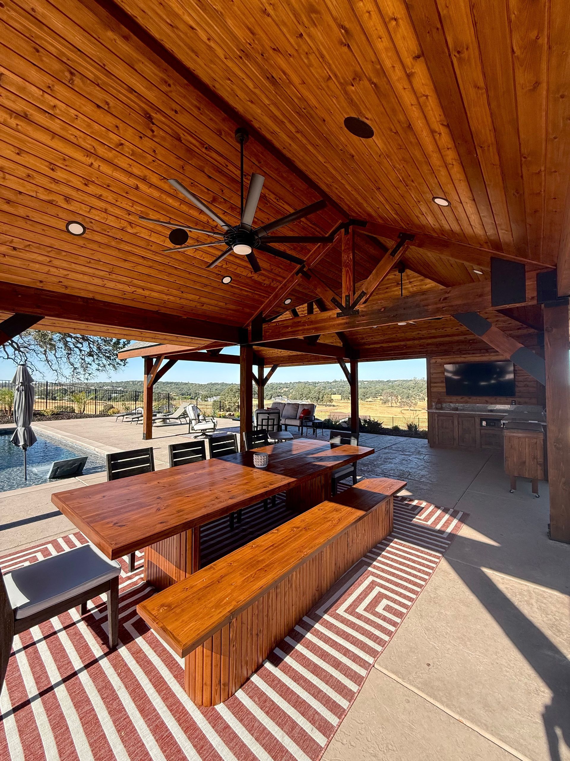 Outdoor patio with wood ceiling, tables, benches, and views of the landscape.