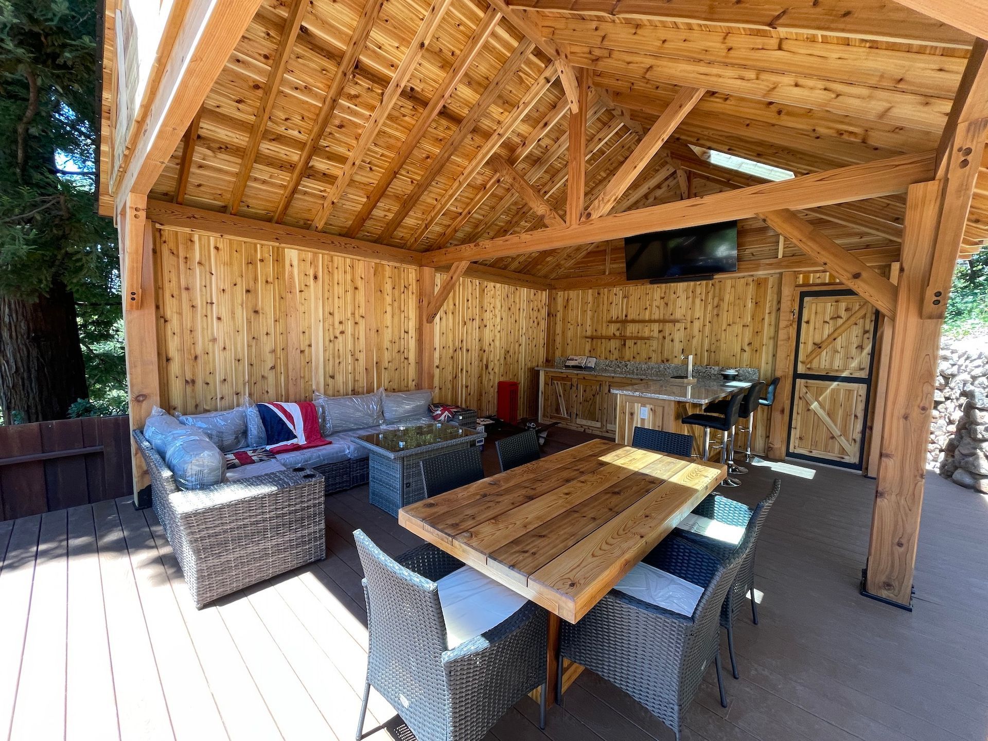 There is a table and chairs under a wooden roof.