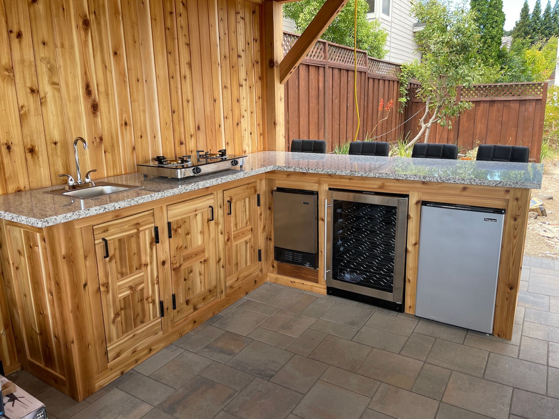 A kitchen with wooden cabinets , granite counter tops , a sink and a refrigerator.