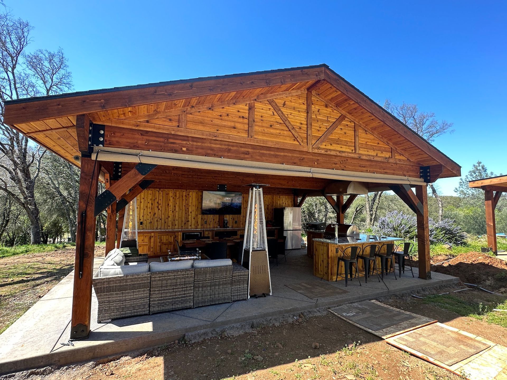 A large wooden pavilion with a kitchen and a television on the roof.