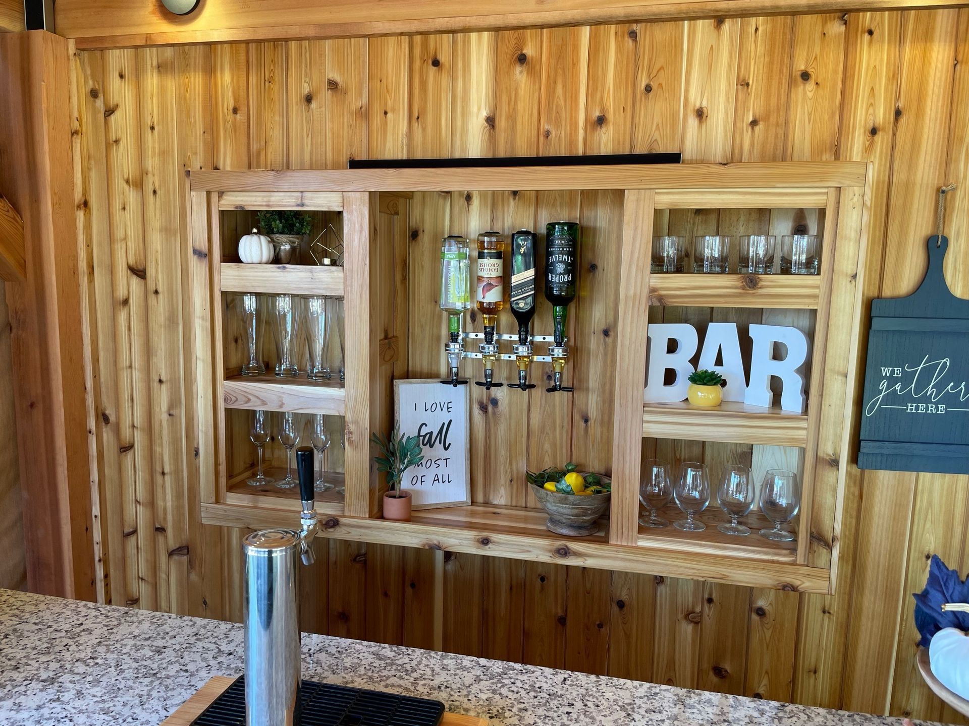 A wooden bar with bottles , glasses , and a sign that says bar.