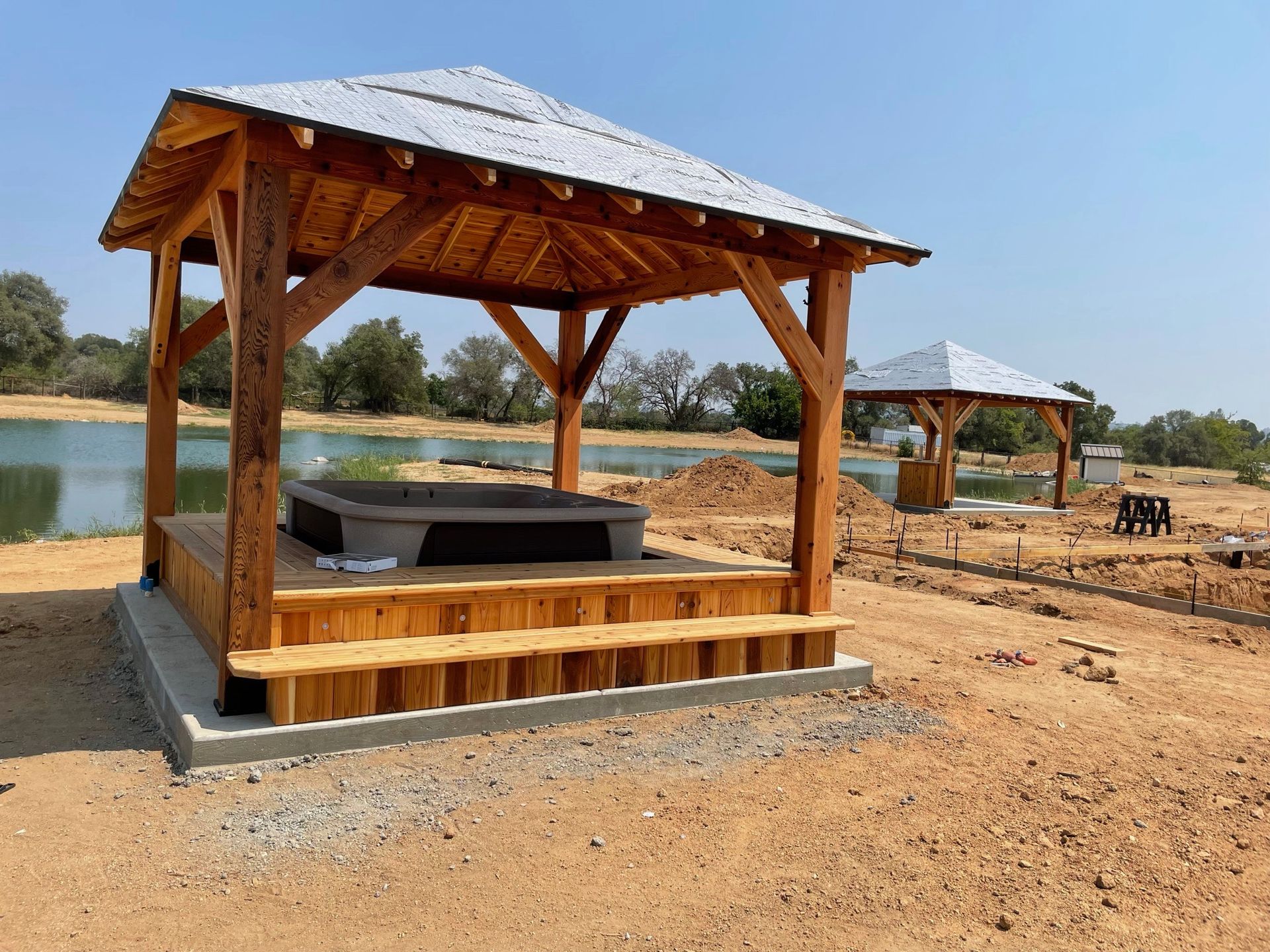 A wooden gazebo with a hot tub underneath it