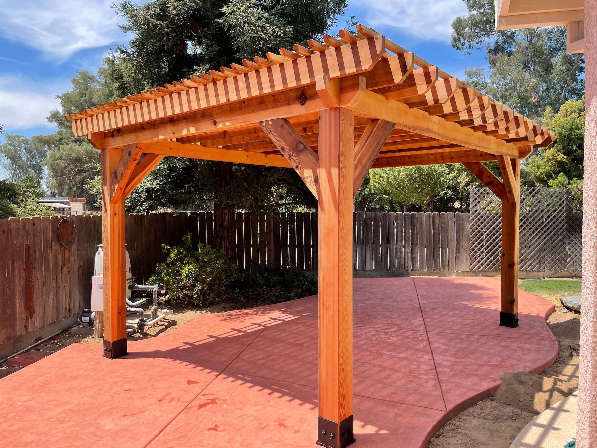 A wooden pergola is sitting on top of a concrete patio in a backyard.