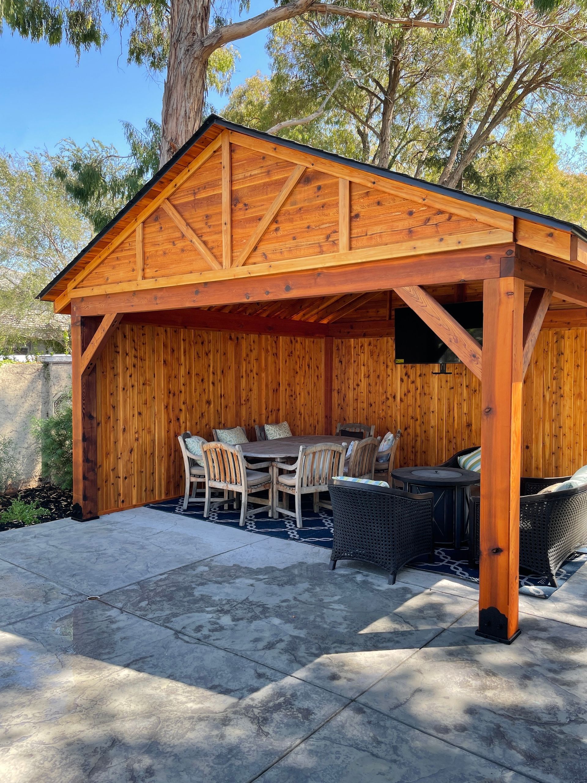 A wooden pavilion with a table and chairs underneath it.
