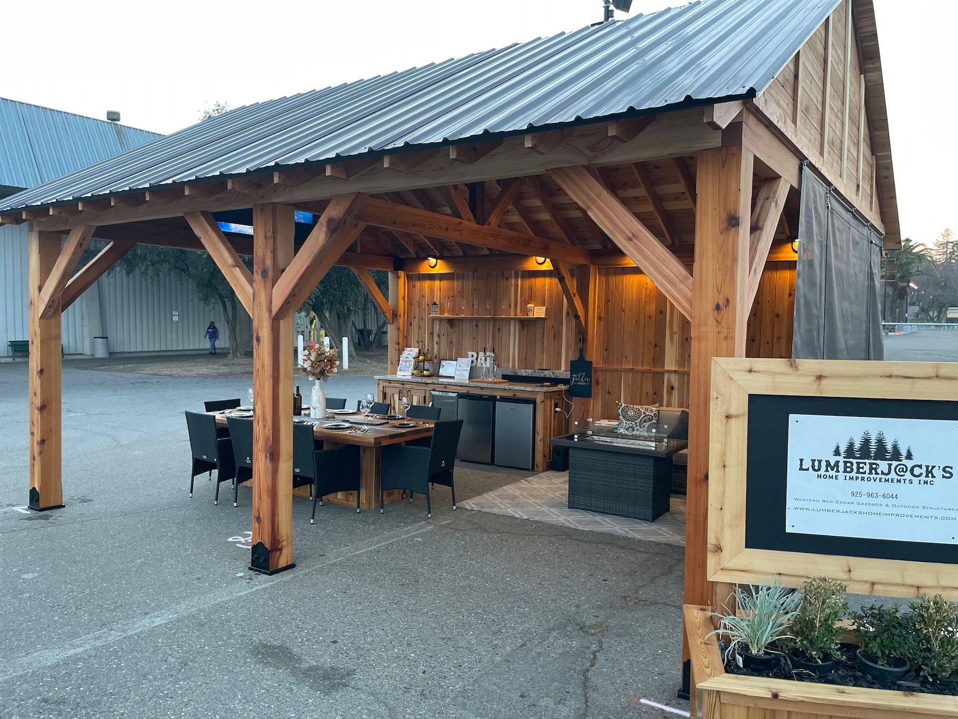 A wooden pavilion with a table and chairs underneath it.